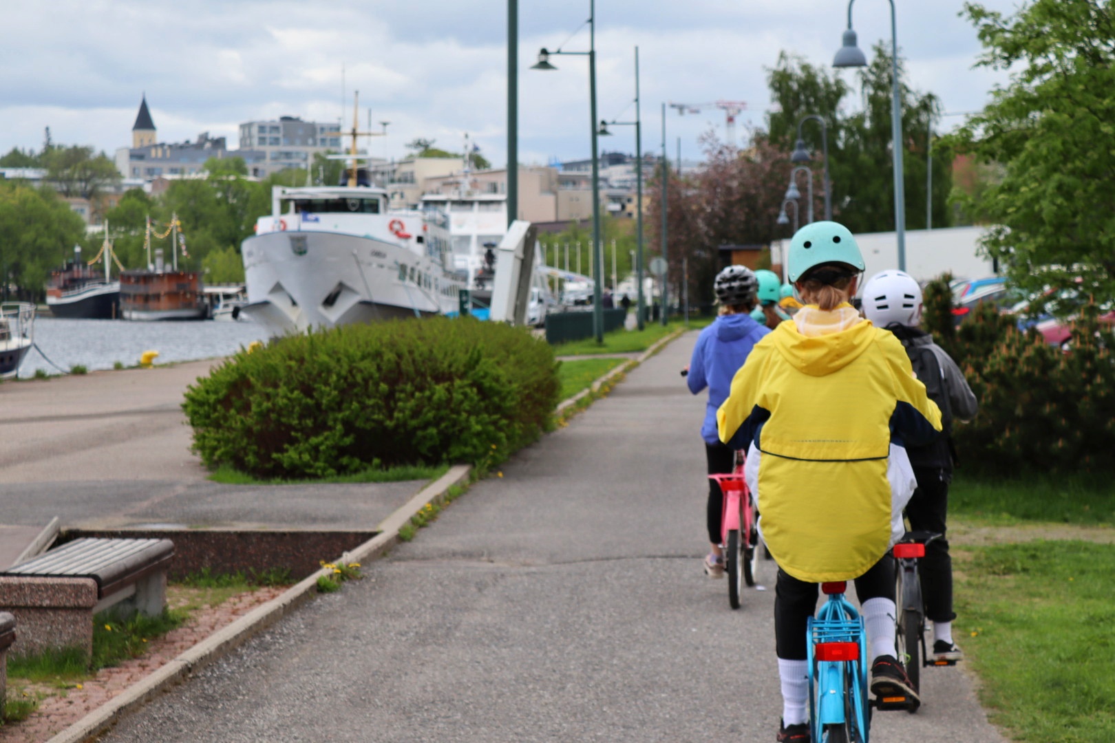 Kolme lasta pyöräilee laivojen vieressä kohti Lappeenrannan satamatoria. 